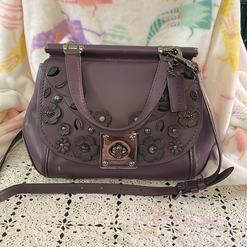 detailed with many leather flowers and stones son the front flap. like new bag..